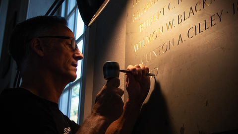 Nicholas Benson, a stone carver from the John Stevens Shop, chisels the name of Clinton A. Cilley into a stone plaque of Harvard Medal of Honor recipients. 