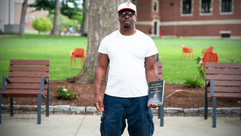 Richard Johnson, holds a copy of his book, Turn Little Wins Into Big Wins: Ignite the Light Within You, at Clark University in Worcester. 
