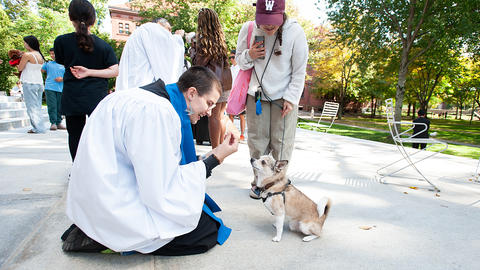 Marty Martinage kneels and blesses Nacho, a tiny dog on the Memorial Church Porch