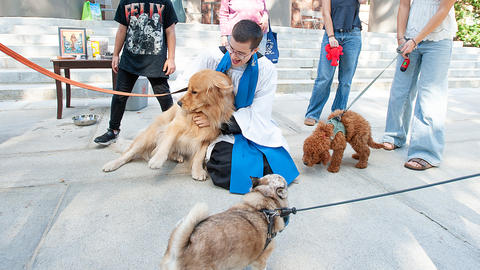 MemChurch Seminarian Marty Martinage MDiv III cuddles a golden retriever on the porch of the church. 