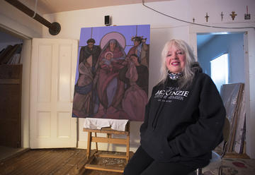 Janet McKenzie in her studio with her painting “Jesus of the People.”
