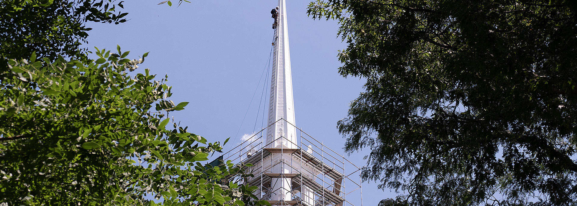 A crew member climbs up the Memorial Church steeple for maintenance. 