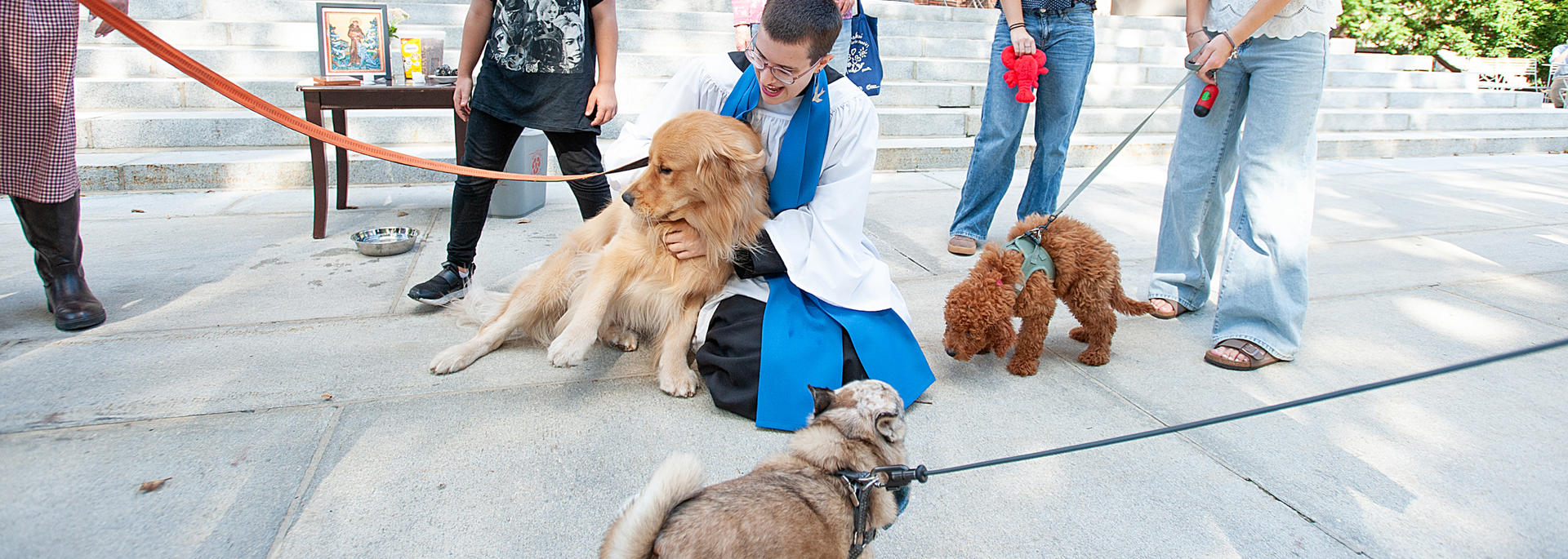 MemChurch Seminarian Marty Martinage MDiv III cuddles a golden retriever on the porch of the church. 