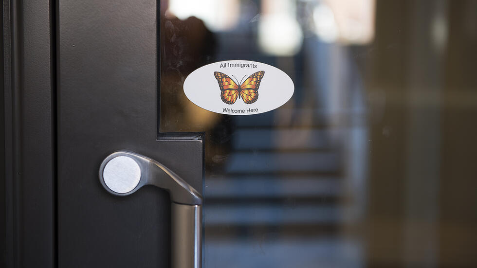 A sticker on the entrance of the Student Oasis welcomes immigrants.